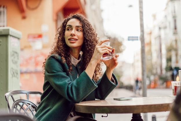A traveler sitting at a cafe in a bustling city, holding a glass of water and smiling, with a plate of fresh fruits and vegetables on the table. The image represents the importance of staying hydrated and nourishing your body with healthy foods while traveling.