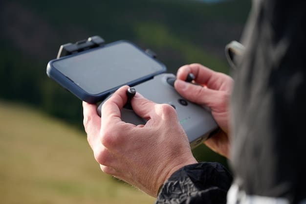 A close-up shot of a drone pilot holding a remote control in a National Park. The pilot is looking intently at the drone, focusing on the flight path. In the background, a picturesque landscape with mountains and trees.