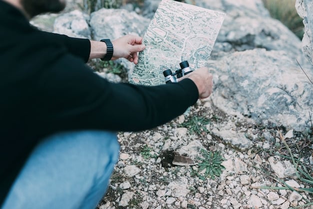 A close-up shot of a topographic map and compass laid out on a rock, with a hand pointing to a specific location on the map. The map shows a trail winding through mountainous terrain.