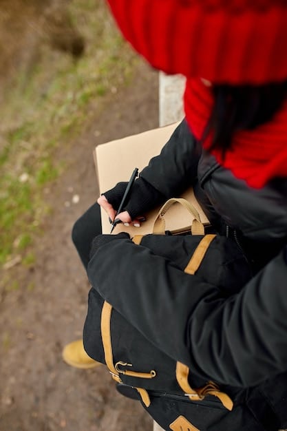 A close-up of hiking gear, including a waterproof jacket, hiking boots, a map, a compass, and a first-aid kit spread out on a rocky surface.