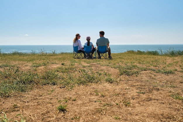 A family with a member using a wheelchair enjoys a scenic overlook in a national park. The overlook features a paved surface and safety railings, providing unobstructed views of the surrounding landscape.