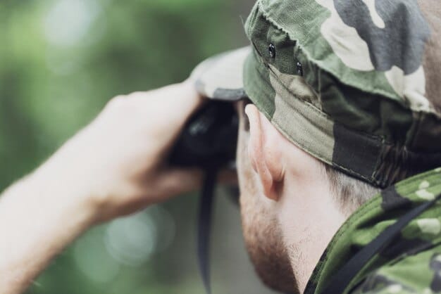 A close-up shot of a ranger in a national park using binoculars to monitor a specific endangered species, such as a bird or mammal. The ranger is surrounded by natural vegetation, highlighting their role in conservation.