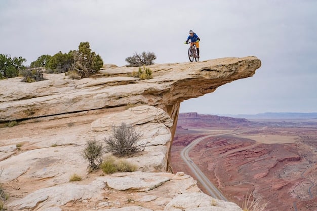 A mountain biker riding down a steep, rocky trail in Moab, Utah, with red rock formations visible in the background, capturing the thrill and challenge of mountain biking in a desert environment.