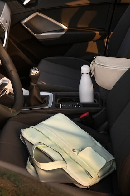 A car's interior is shown with various organizers in place, including seat-back organizers with pockets filled with travel items, a console organizer between the seats, and a trash can in the backseat. The image shows how to maximize space and keep items organized.