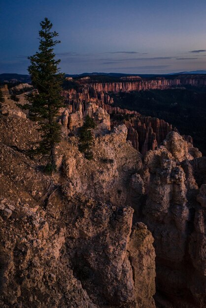 A dramatic view into the Black Canyon of the Gunnison National Park. The steep, dark, and rugged cliffs rise sharply from the Gunnison River, with the blue sky visible above.